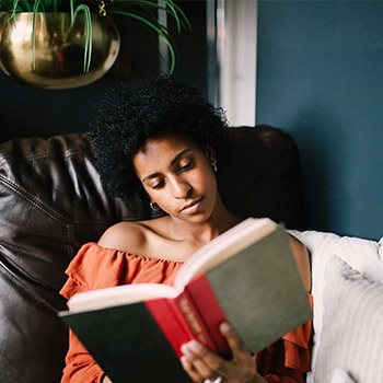 femme assise sur un fauteuil lisant un livre