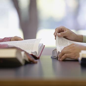 livres sur une table et des mains des personnes qui lisent