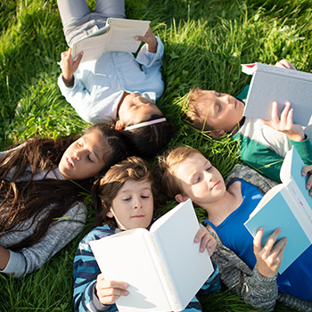 enfants allongés sur une pelouse avec chacun un livre ouvert