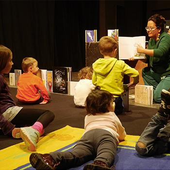 femme assise avec enfants montrant un livre
