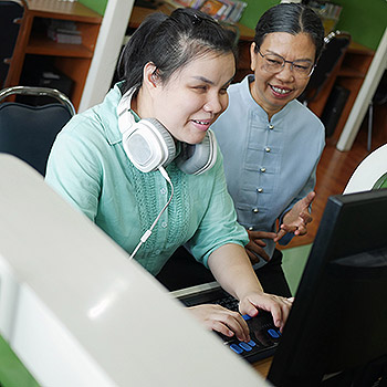 femme handicapée sur ordinateur avec une assistante