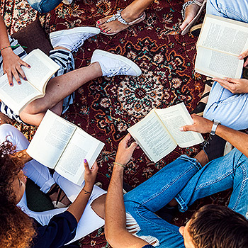 groupe adolescants assis en rond sur tapis avec des livres